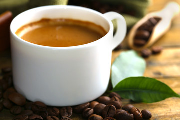Cup of coffee with beans on table close up