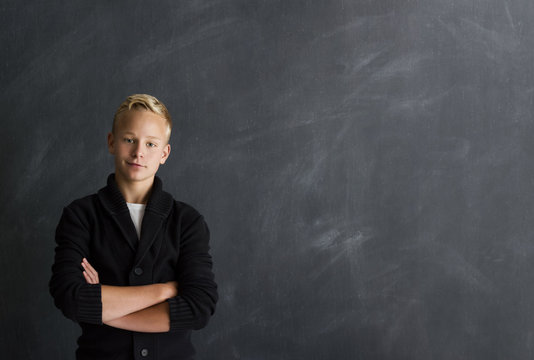 Junge mit verschr&auml;nkten Armen vor Tafel