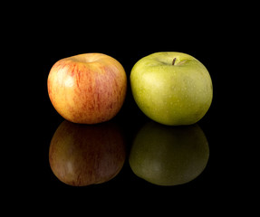 Fototapeta na wymiar Two apples on a black mirror surface