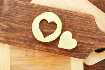 Apple slice with cut in shape of heart on wooden background