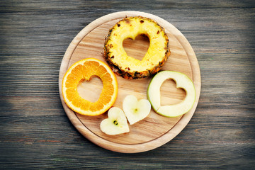 Fruits slices with cut in shape of heart on wooden background