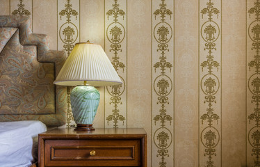 Vintage interior with jade stone desk lamp, bed, nightstand and wallpaper