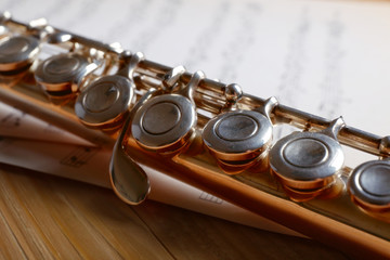 Naklejka premium Silver flute with music notes on wooden table close up