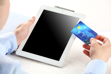 Man holding credit card and tablet on workplace background