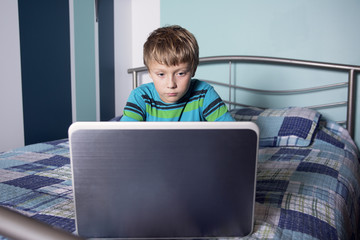 Young boy on bed with laptop