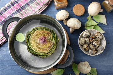 Artichokes in pan on cutting board, on  wooden background