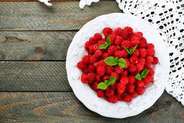 Fototapeta na wymiar Sweet raspberries on plate on wooden background