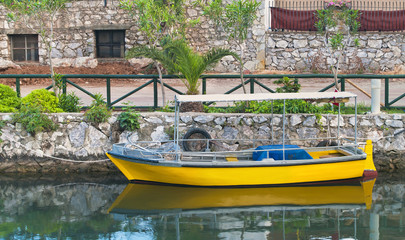 Fototapeta na wymiar small yellow boat moored in canal