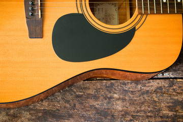 half of an acoustic guitar on a wooden background