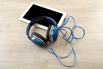 Headphones with tablet on wooden table close up