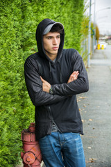 Fototapeta na wymiar Handsome young man in black hoodie sweater standing outdoor 