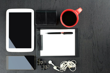 black background, red cup, headphones, phone, tablet. paper holder, pen