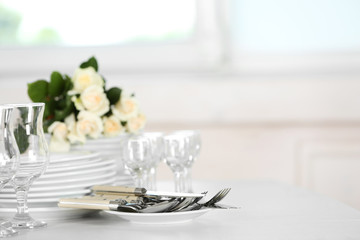 Clean plates, glasses and cutlery on white table