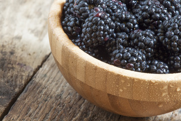 Fresh blackberries in a wooden bowl, selective focus