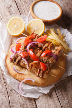 Greek kebab with tomatoes, onions and french fries on pita bread 
