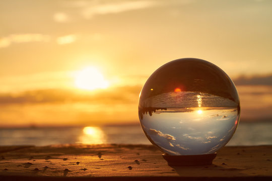 Die Sonne geht &uuml;ber dem Bodensee unter und leuchtet durch eine Glaskugel.