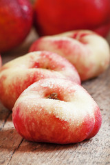 Flat pink nectarine on an old wooden background, selective focus