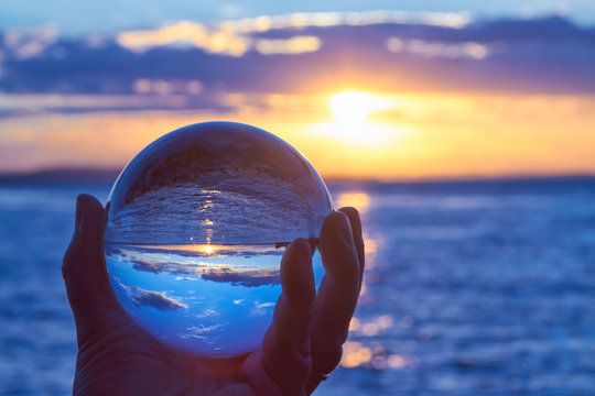 Die Sonne geht &uuml;ber dem Bodensee unter und leuchtet durch eine Glaskugel.