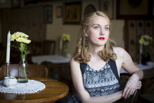 Beautiful young woman waiting at a table in old cafe.