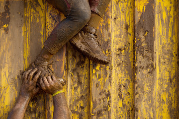 Mud race runners assistance for breakthrough - obrazy, fototapety, plakaty