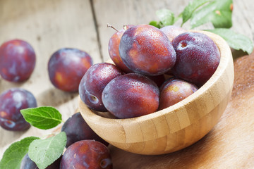 Blue plum poured from a wooden bowl, selective focus