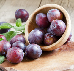 Blue plum poured from a wooden bowl, selective focus