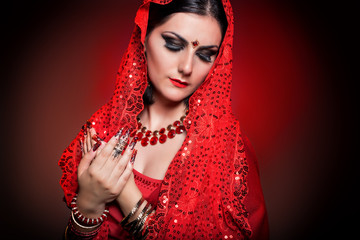 beautiful girl in the image of Indian woman in a red sari with beautiful patch acrylic nails in oriental style in the studio