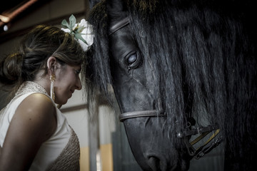 Bailaora de flamenco con caballo negro Árabe. Gitana flamenca y su caballo negro Árabe. Espectáculo de baile flamenco con caballos.