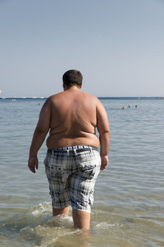 uomo obeso che entra in acqua