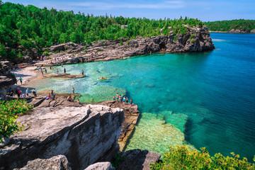 Bruce Peninsula at Cyprus lake, Ontario stunning, gorgeous amazing natural rocky beach view and tranquil azure clear water with people in background on sunny beautiful, day - obrazy, fototapety, plakaty