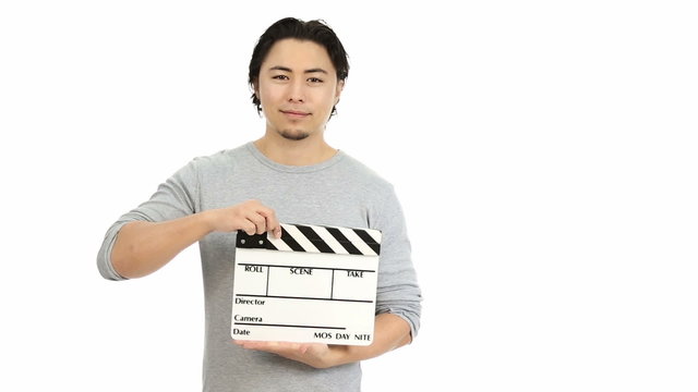 Man in his 20s holding a film slate wearing a grey shirt. White background.