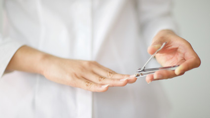 close up shot of a woman cutting her nails with shallow depth of field, focus on nail clipper