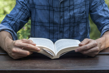 youngman reading a book on a wooden garden table