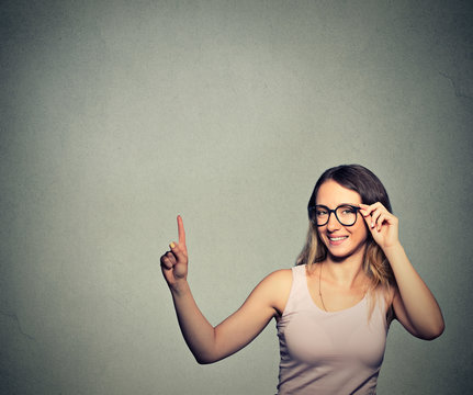 woman with glasses pointing up with finger at blank copy space