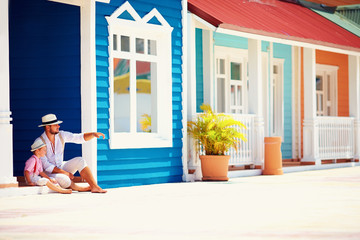 fashionable father and son sitting and talking on caribbean street