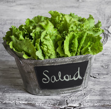 fresh green salad in a vintage  bucket on light wooden surface