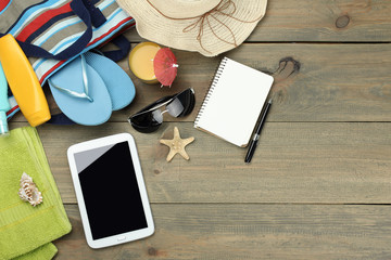 wood background, sunblock, phone, shell, beach flip flops, bags, sunglasses, cocktail, starfish. hat, towel,pad