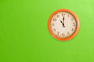 Fototapeta na wymiar Clock showing 11:00 o'clock on a green wall 