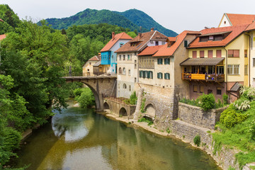 Fototapeta na wymiar Stone bridge over the river and houses directly above it.