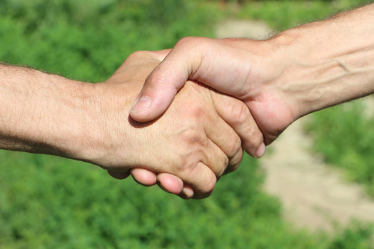 Suntanned male hands make handshake