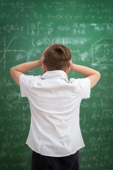 Upset child looking at blackboard full of formulas