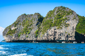 Fototapeta na wymiar Cliff and the clear sea with a boat near Phi Phi island in south