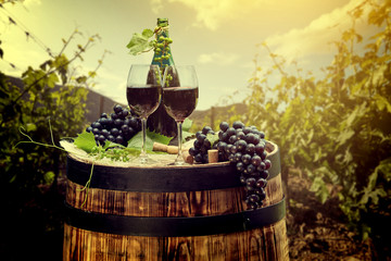 Red wine bottle and wine glass on wodden barrel. Italy