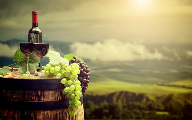 Fototapeta na wymiar Red wine bottle and wine glass on wodden barrel. Italy