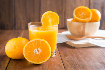 Orange juice in glass, fresh fruits on wooden background