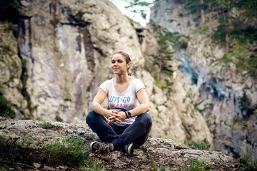 Naklejka na ściany i meble young caucasian female sitting on a cliff in Crimea mountains