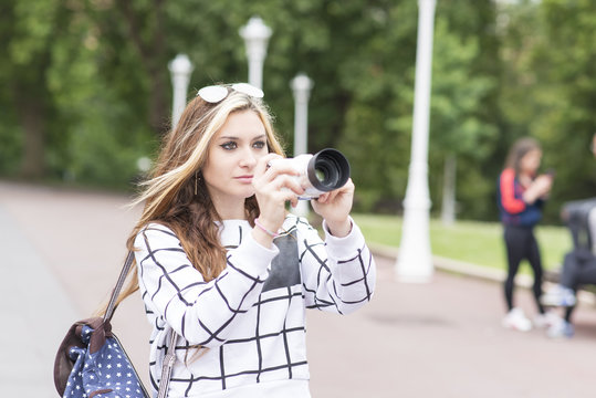 Beautiful woman takes pictures with the camera in the street.