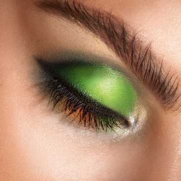 macro photo of closed eyes with professional green colors makeup