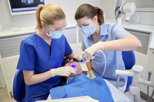 dentists treating male patient teeth at clinic