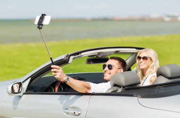 happy couple in car taking selfie with smartphone